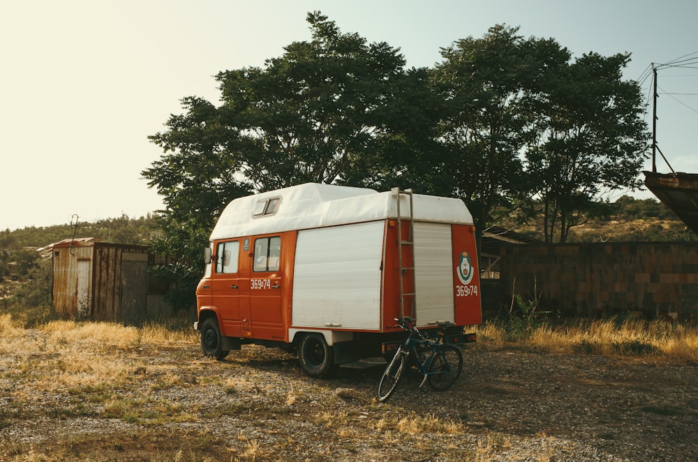 an orange and white trailer parked next to a tree