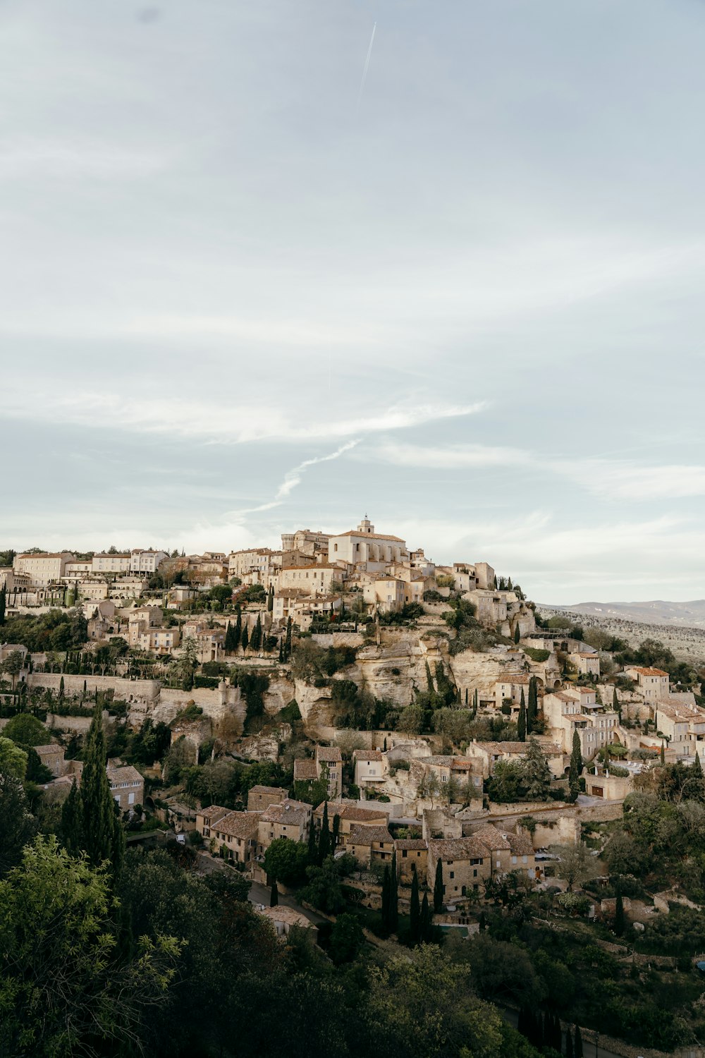 a village on top of a hill surrounded by trees