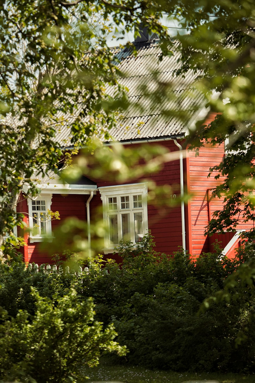 a red house surrounded by trees and bushes