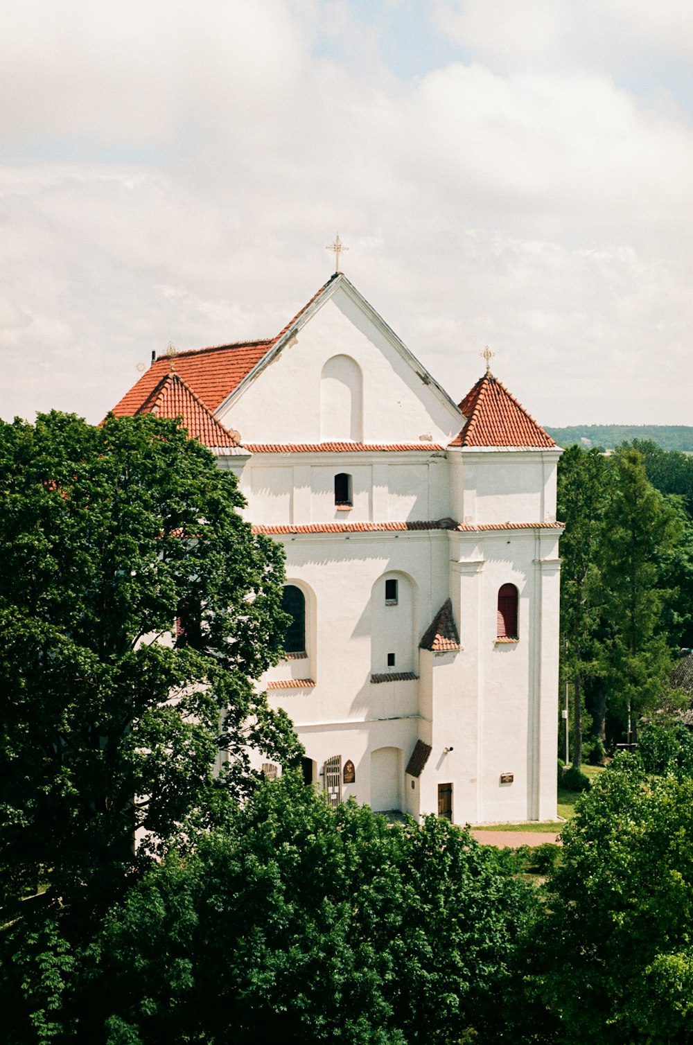 a white church with a red roof surrounded by trees