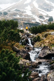A rugged mountain trail with a hiker wearing a sleek waterproof jacket from traildry.