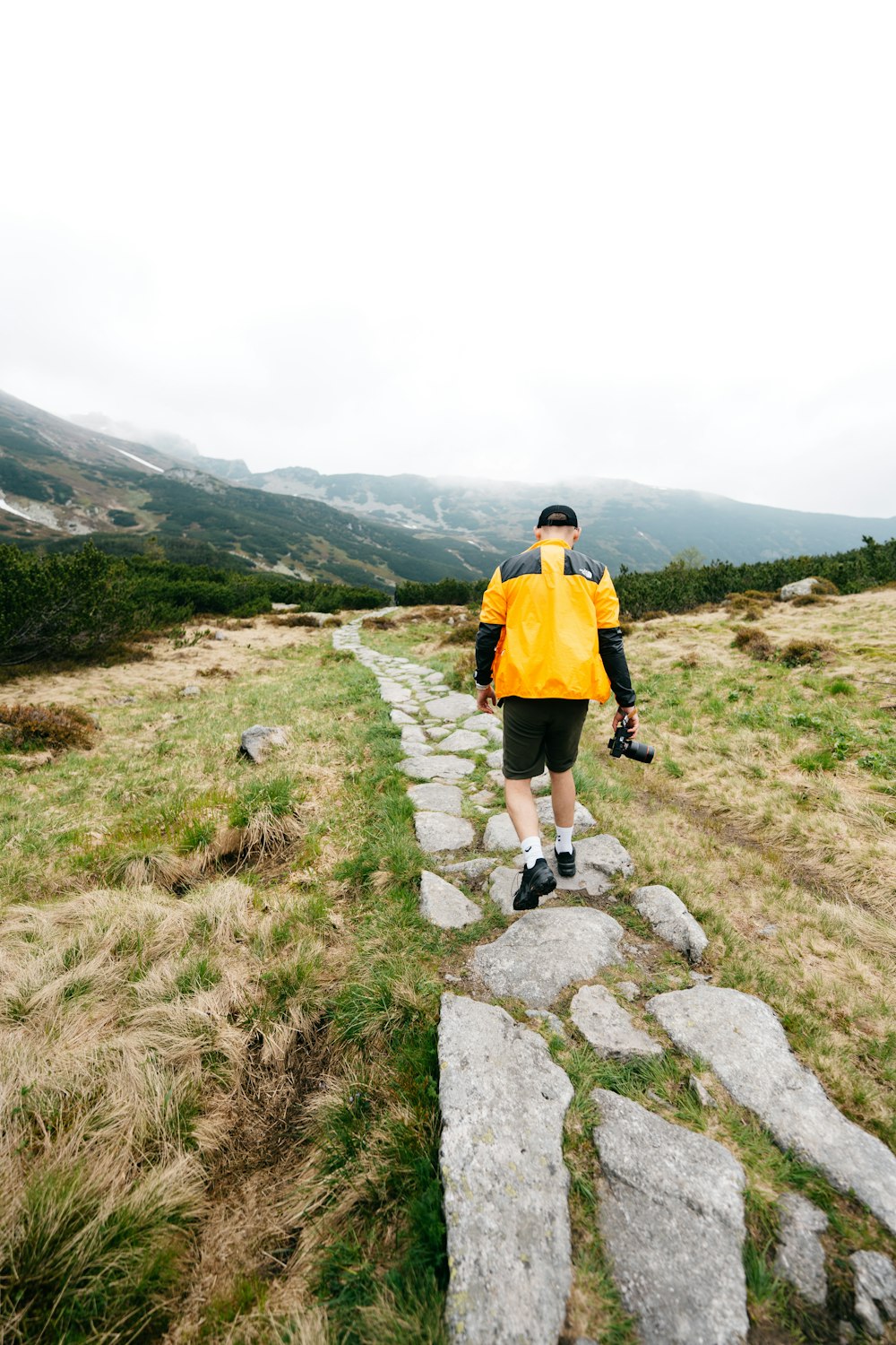 a man walking up a stone path in the mountains