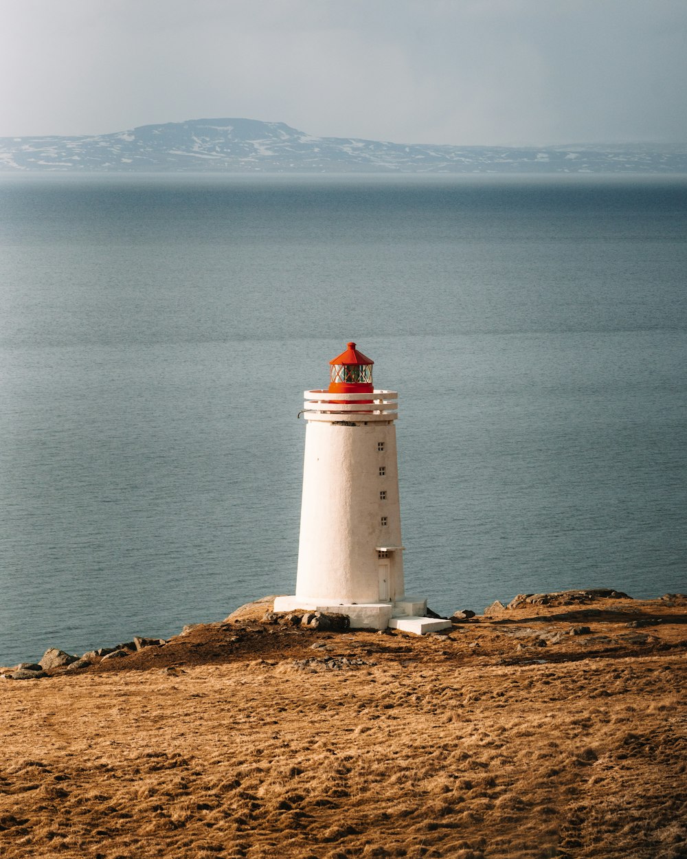 a white and red lighthouse sitting on top of a sandy beach