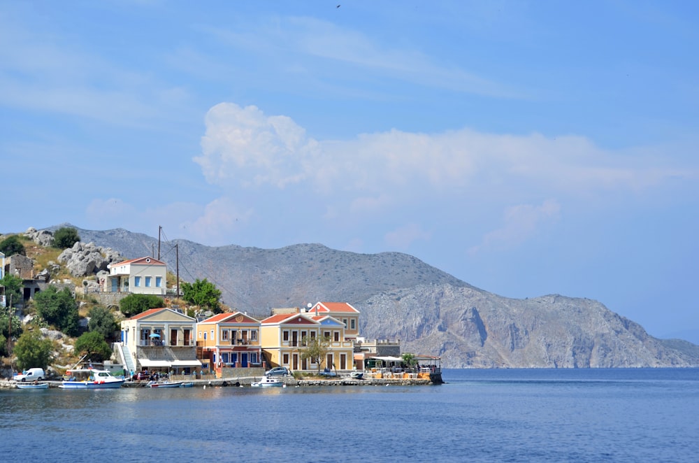 a row of houses sitting on top of a hill next to a body of water