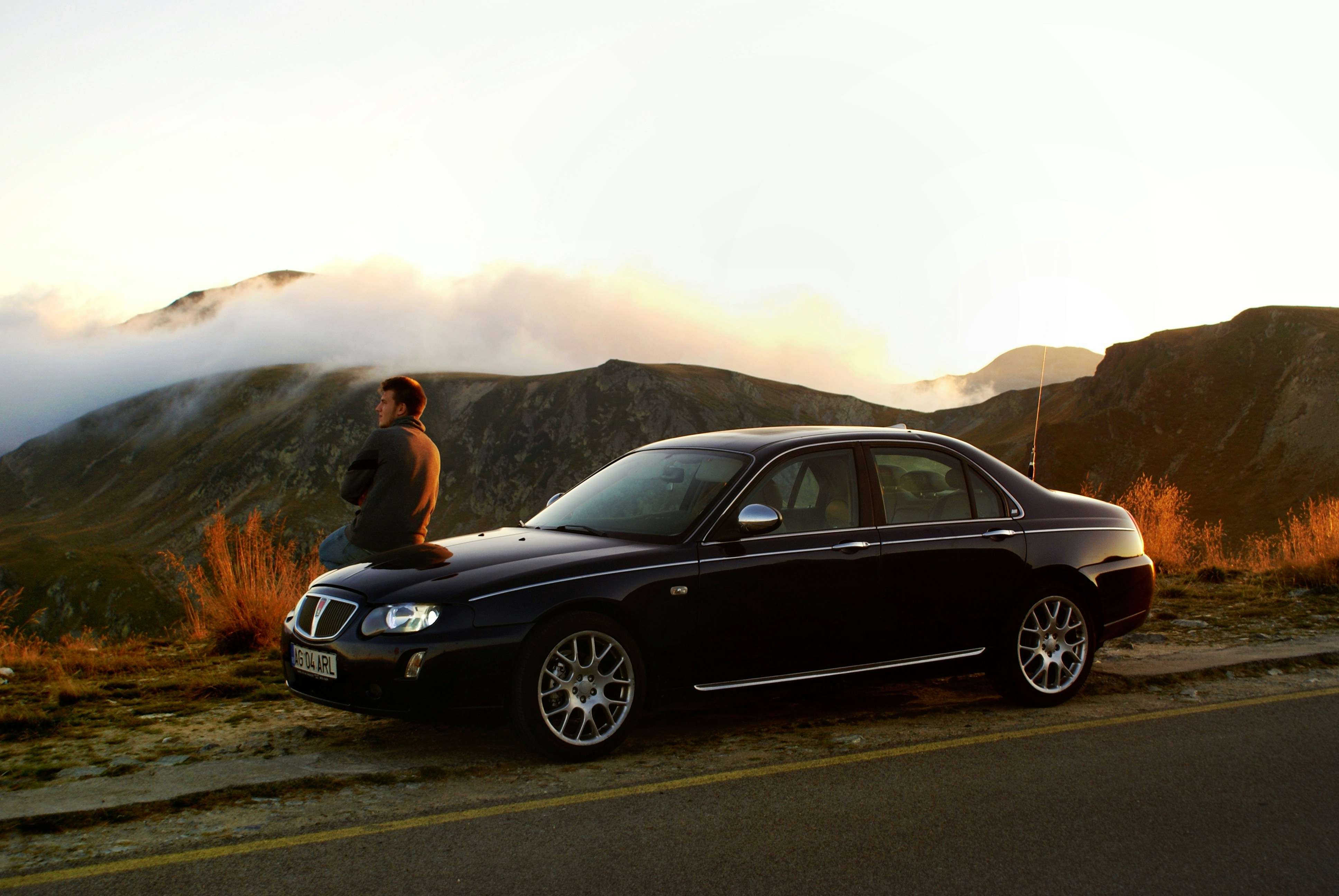 a man sitting on the hood of a black car