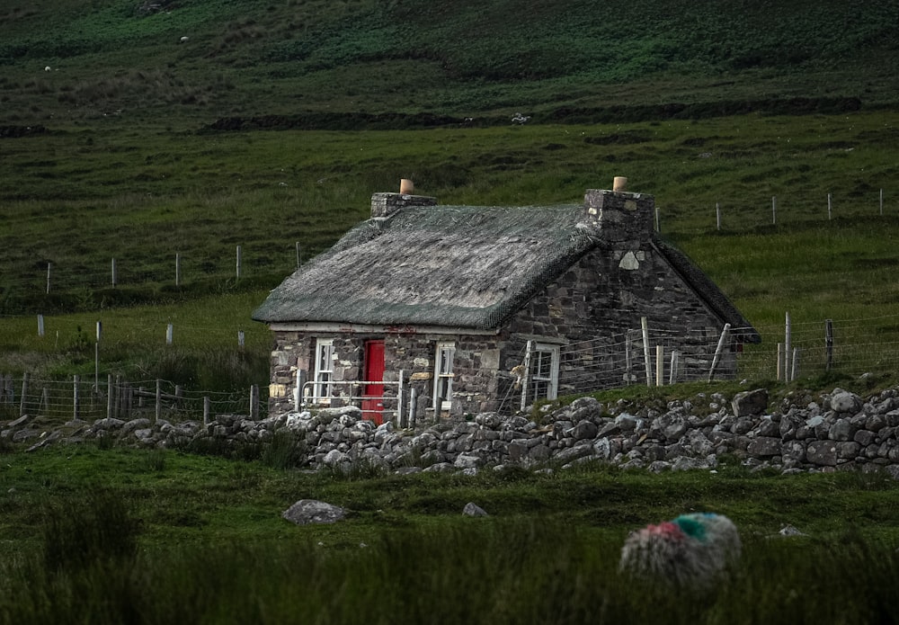 uma casa de pedra com uma porta vermelha e janelas