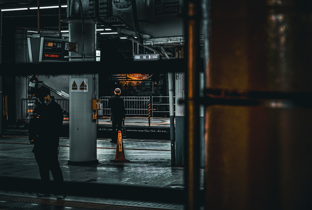 a man standing in a train station next to a pole