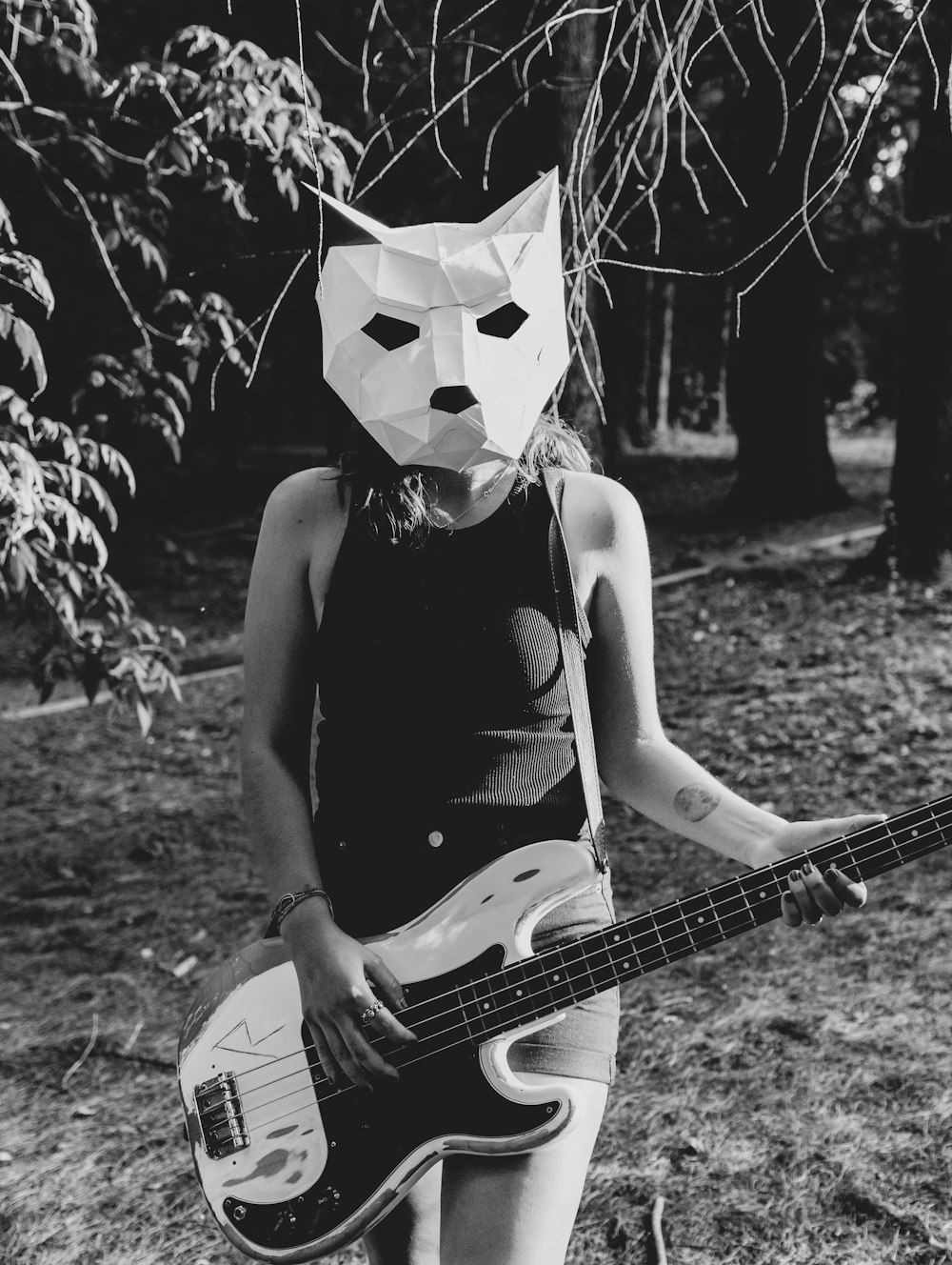 a girl with a paper mask playing a bass guitar