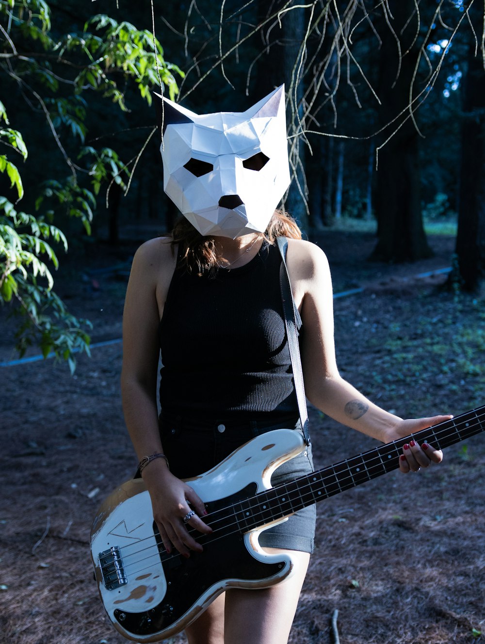 a woman with a cat mask holding a bass guitar