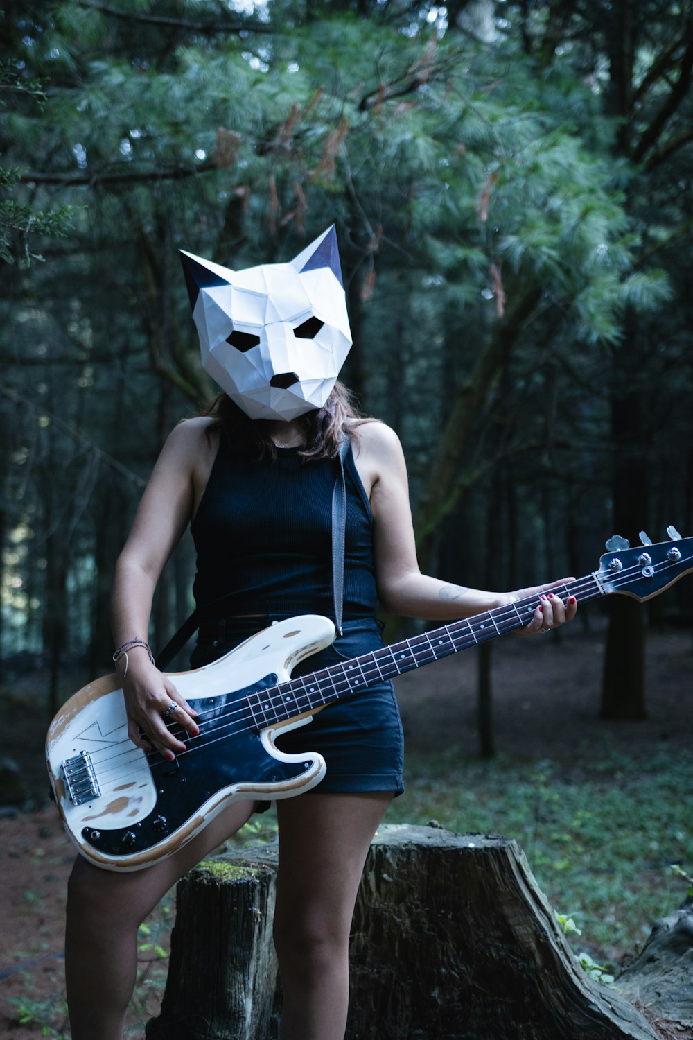 uma mulher usando uma máscara de papel enquanto segura um violão