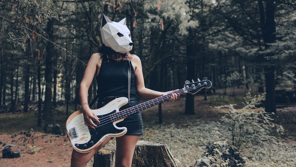a woman wearing a paper mask holding a guitar