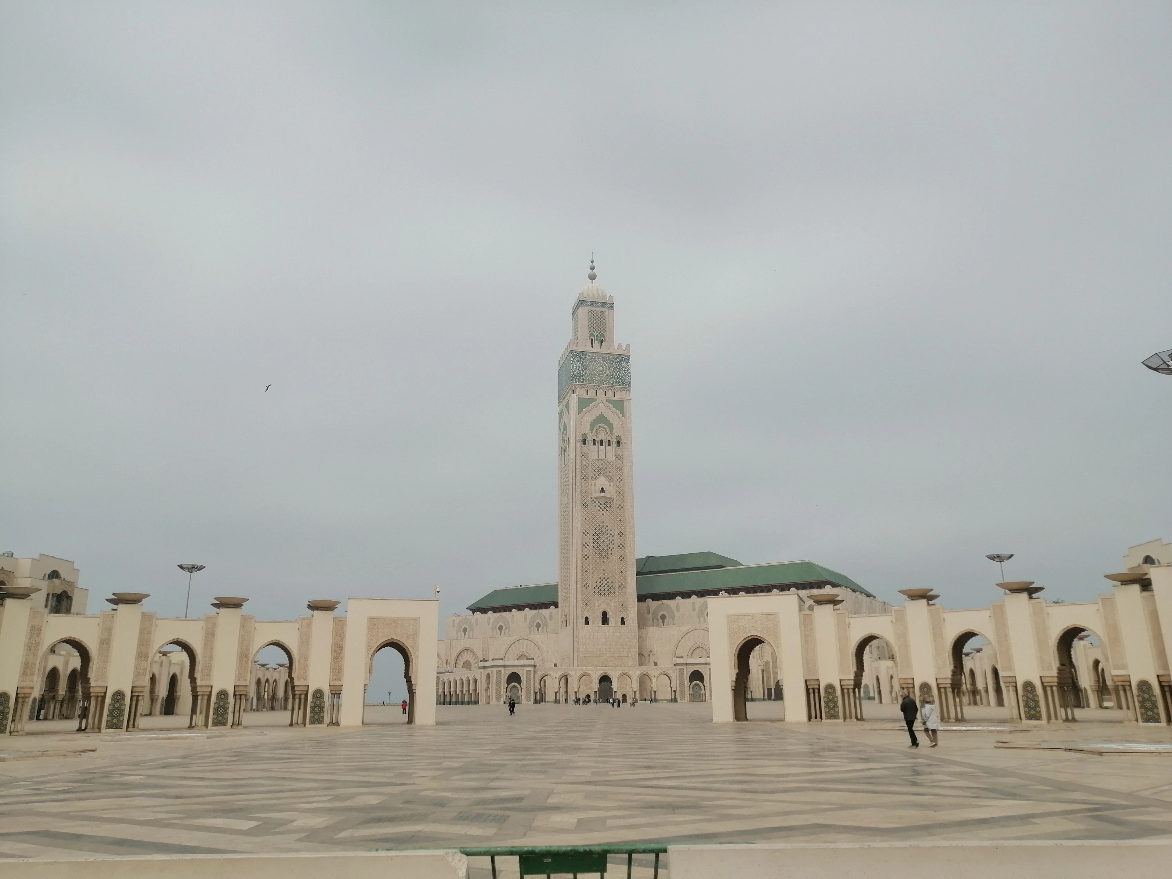 The vast open plaza of the Hassan II Mosque in Casablanca, arcades running the length of one side