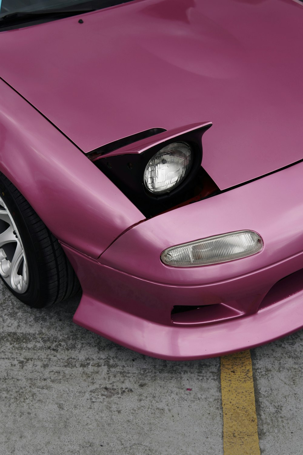 a pink sports car with its hood up