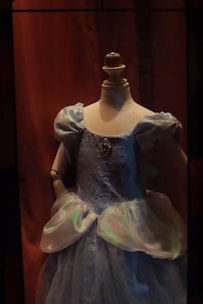 Elegant evening dress in deep blue, displayed on a mannequin with soft lighting.