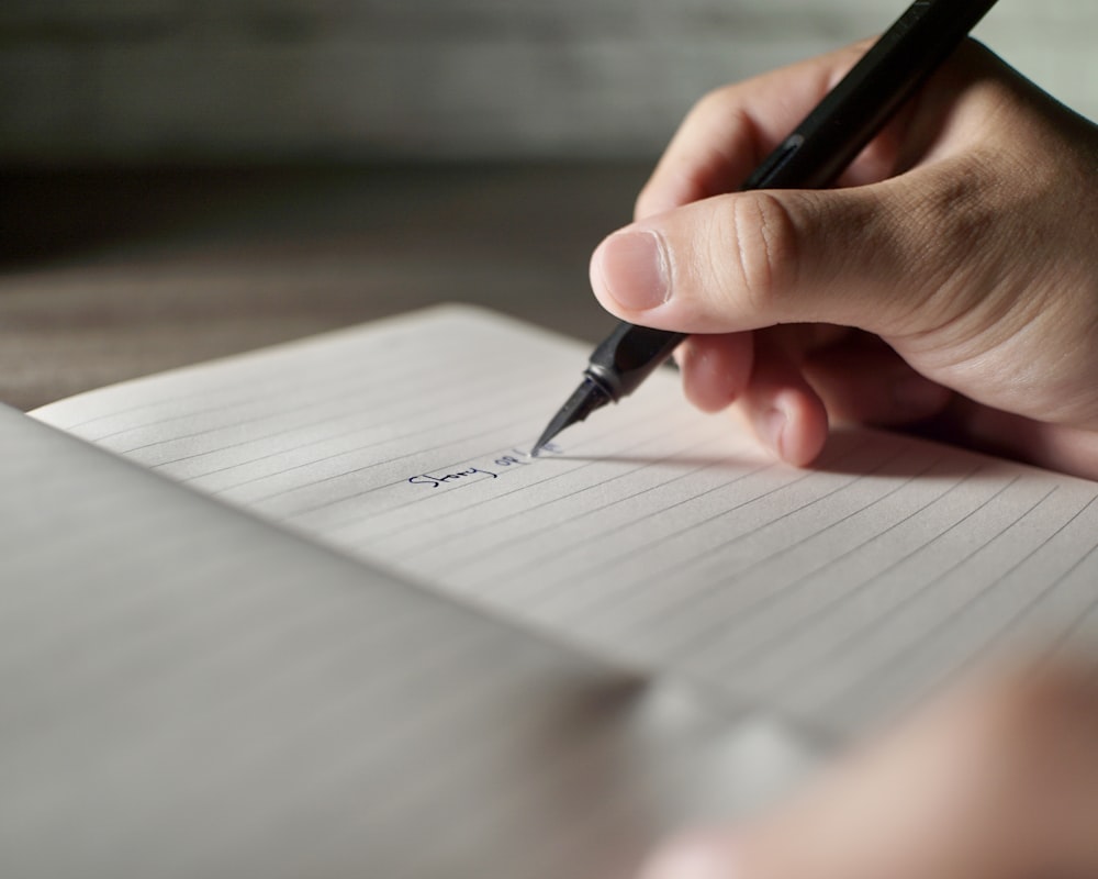 a person writing on a piece of paper with a pen