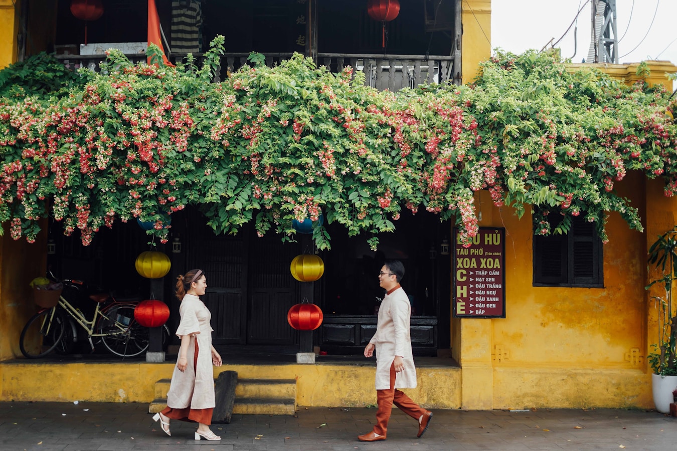 a couple of women walking past a yellow building