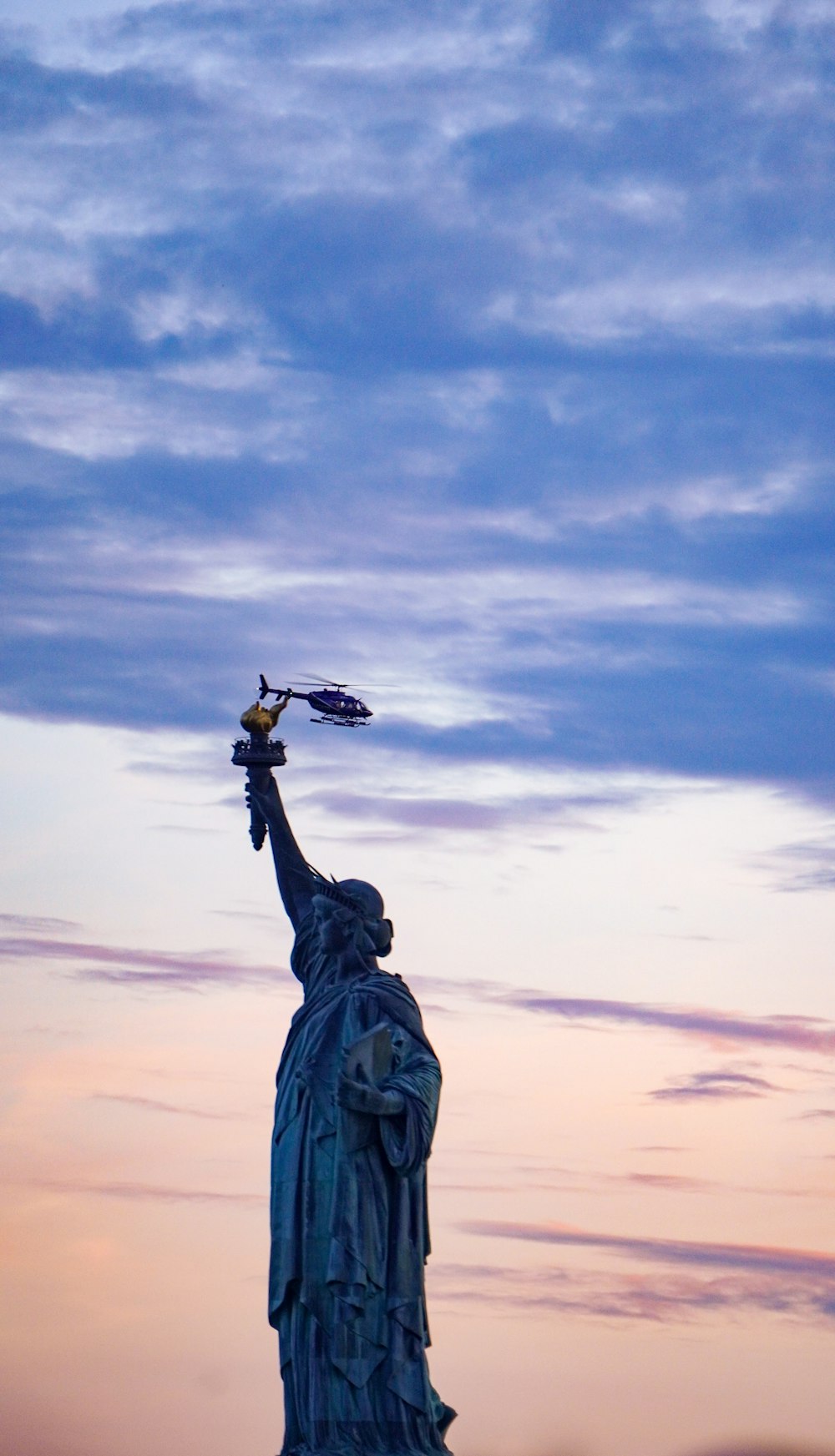 the statue of liberty is silhouetted against a cloudy sky