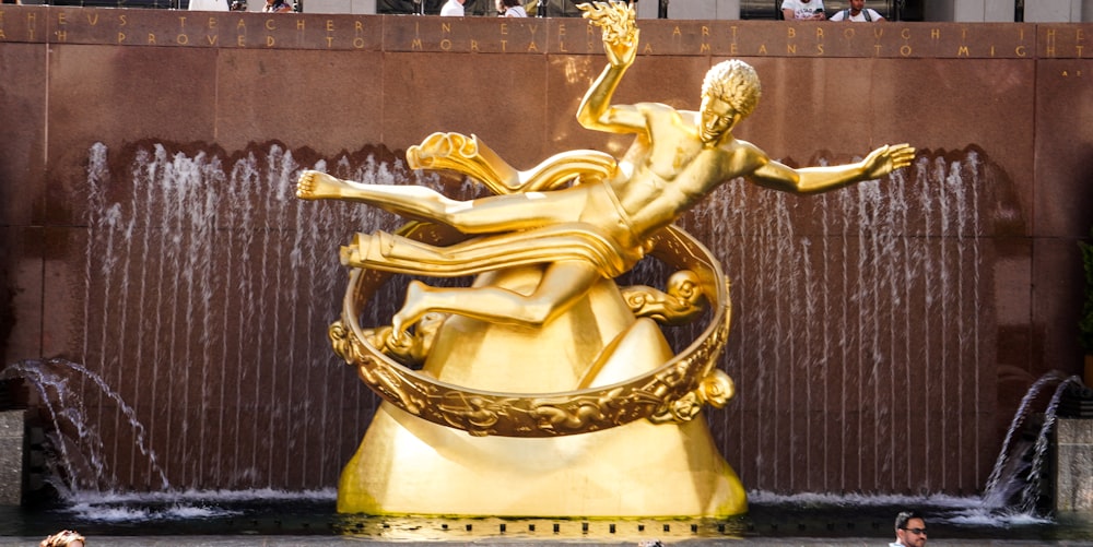 Una statua dorata di un uomo e una donna davanti a una fontana