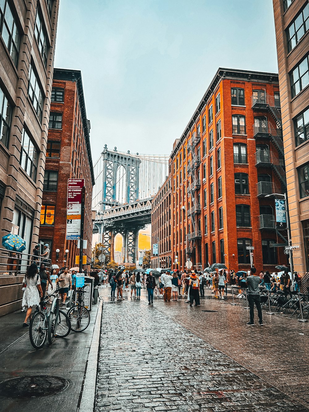 a group of people walking down a street next to tall buildings