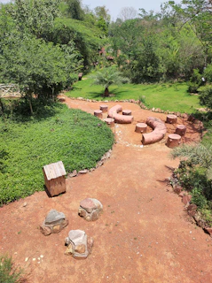 A spacious garden in Riyadh with a mix of native plants, shaded seating areas, and a water feature.
