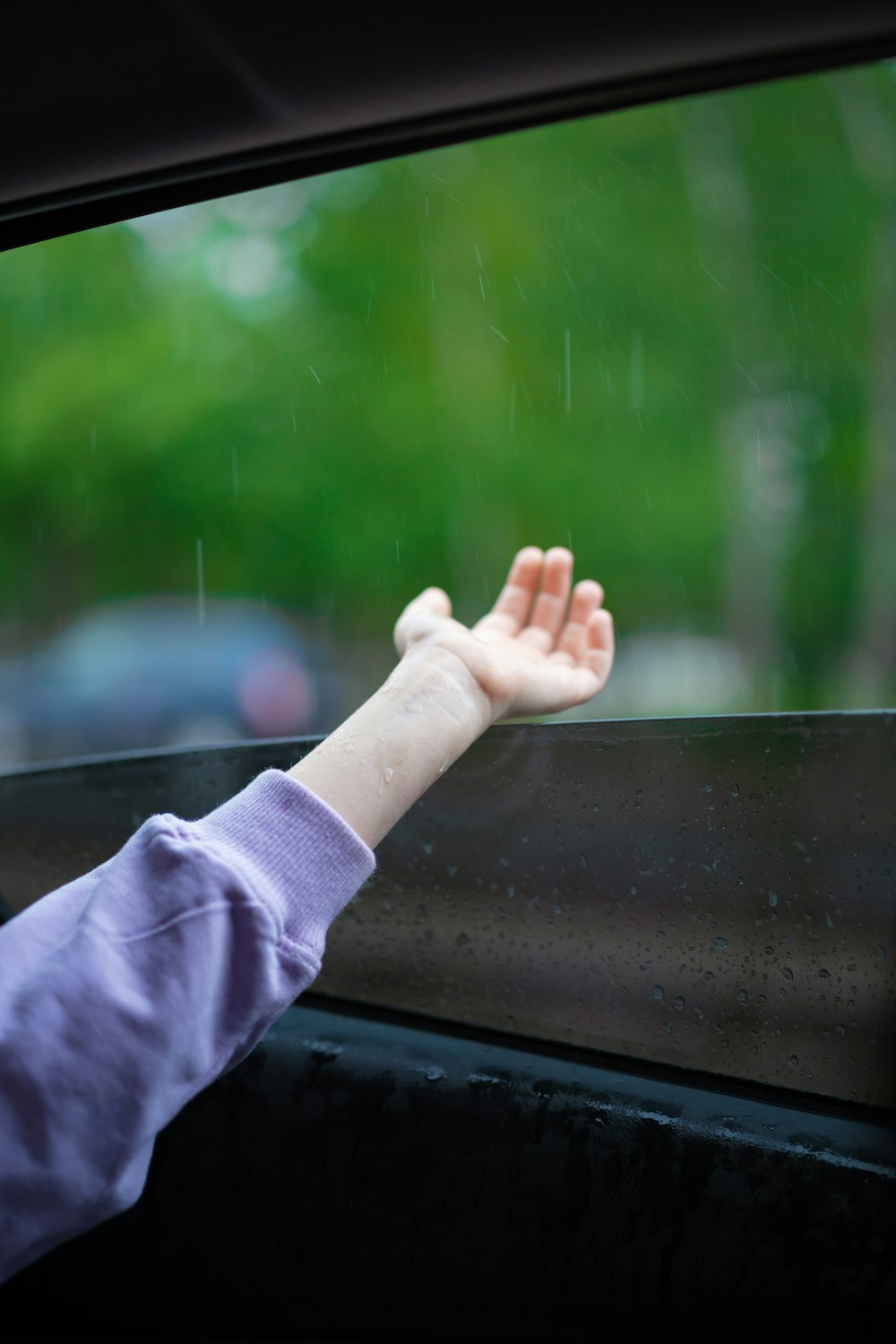 a young child reaching out of a car window
