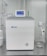 A sleek, modern laboratory water purification system is placed on a stainless steel countertop. The device is predominantly white with a digital control display at the top, featuring the brand logos 'Rephile' and 'Genie'. Surrounding the unit are various laboratory fixtures, including pipes, a pressure gauge, and a clipboard with documentation. A plug with cords is connected on the side, alongside a small transparent container.