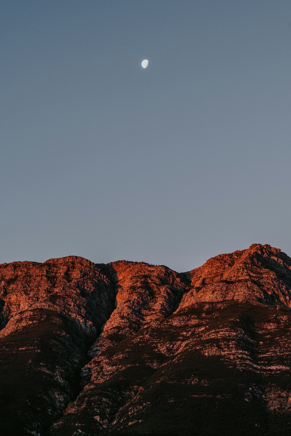 a full moon rising over a mountain range