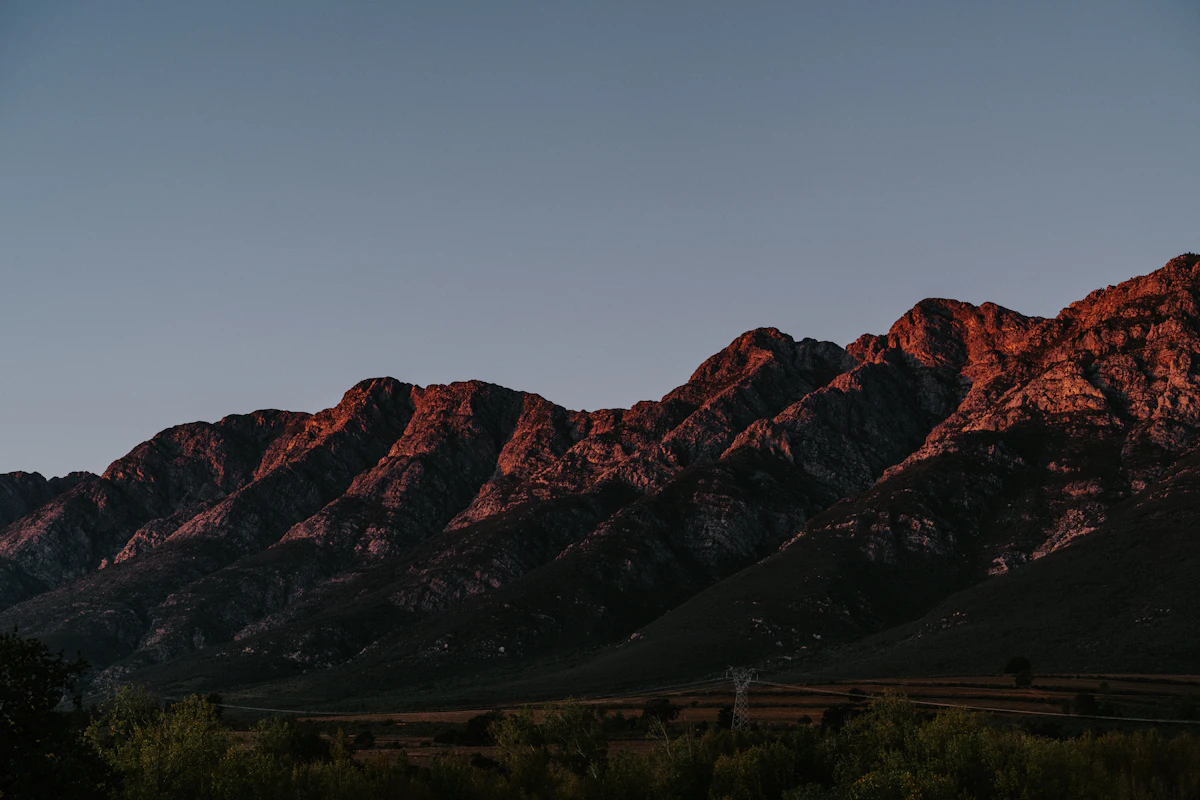 A rugged sandstone range near Tulbagh catching the last light, above dark scrub