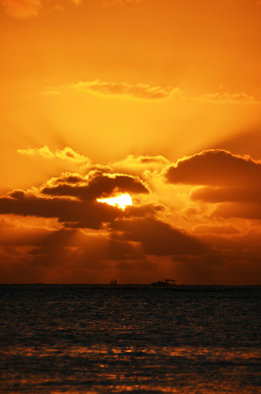 the sun is setting over the ocean with a boat in the distance