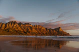 Majestic mountain coastline bathed in warm sunlight with a cruise ship in view.