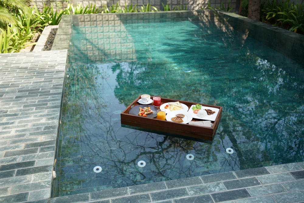a tray of food sitting on the edge of a pool