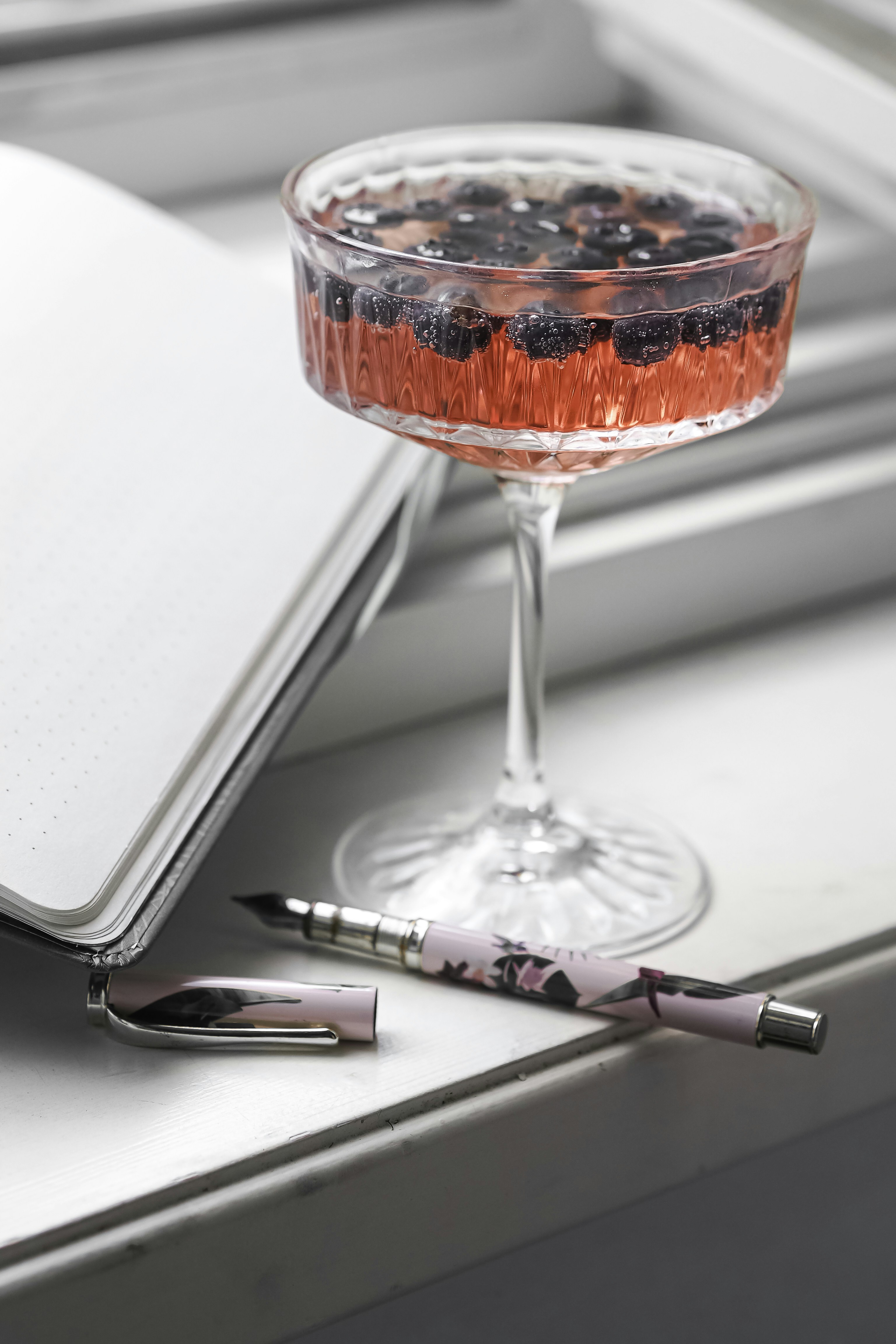 a glass filled with liquid next to a notebook