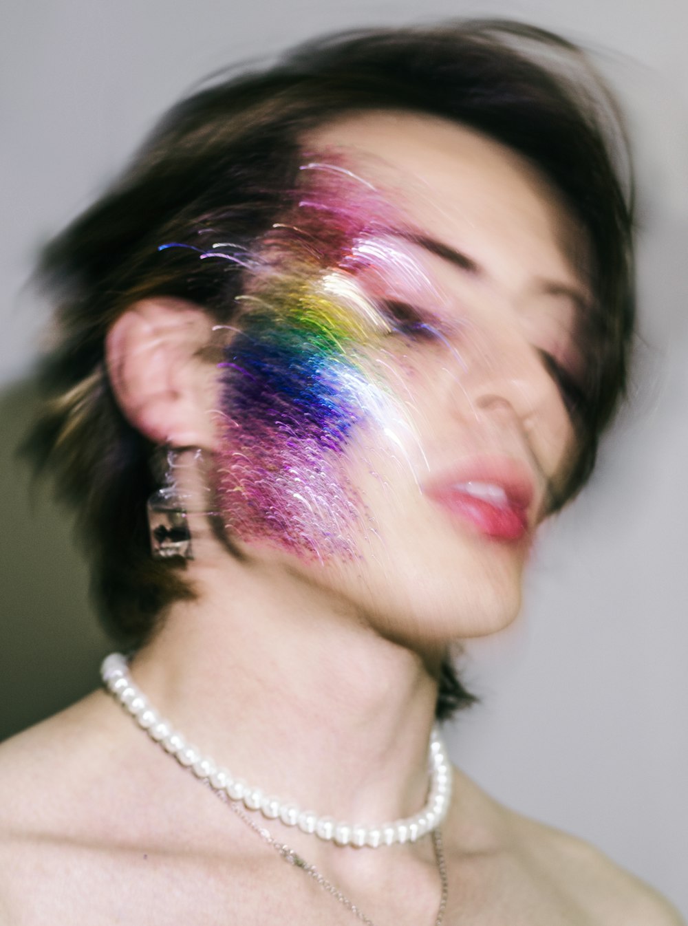 a woman with a multicolored face and necklace