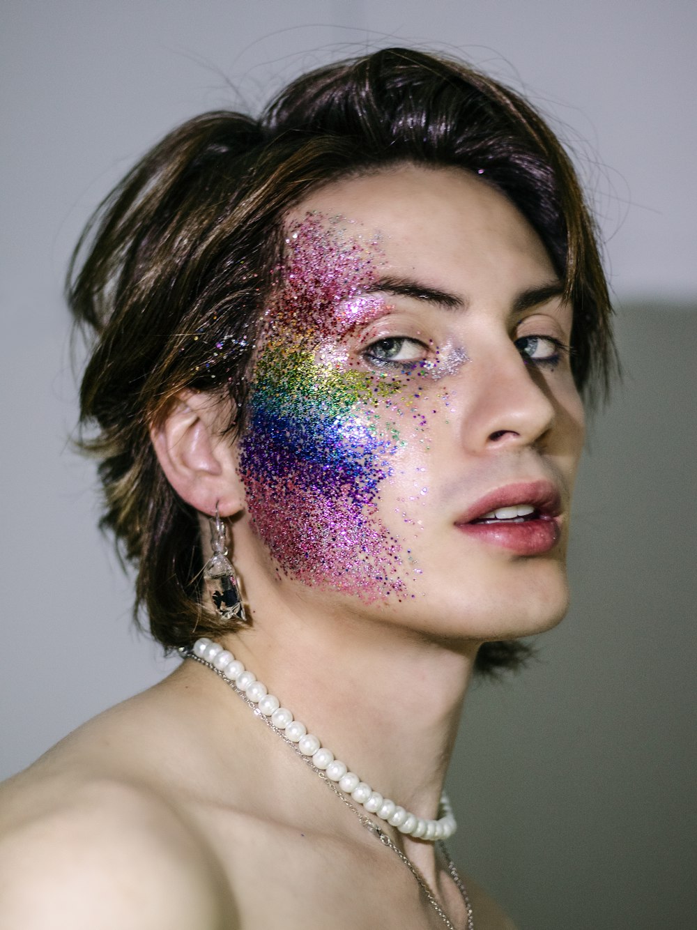 a woman with a multicolored face and a pearl necklace