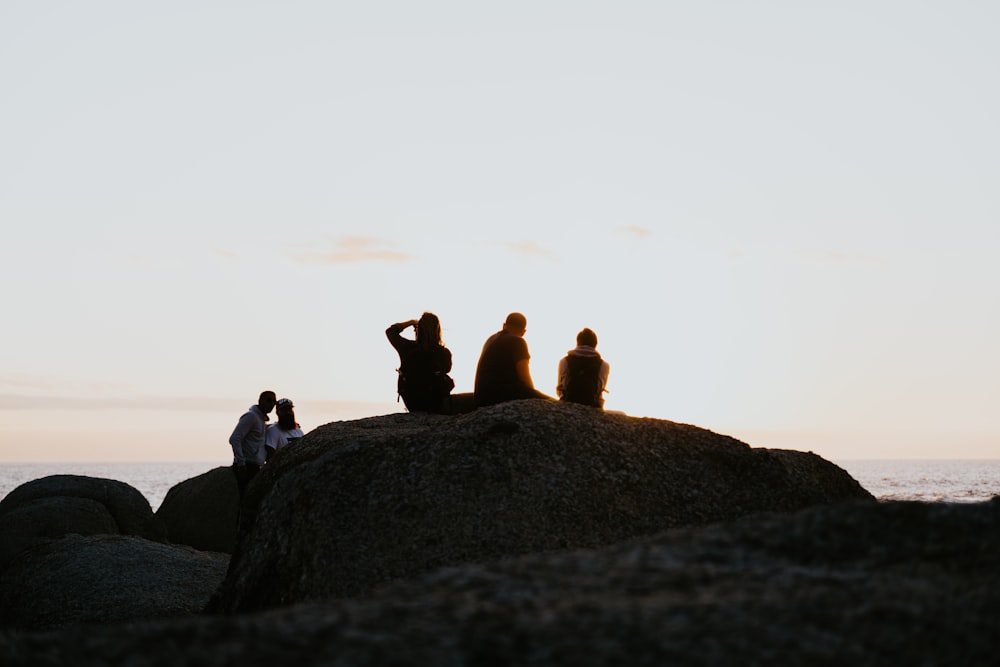 a group of people sitting on top of a large rock