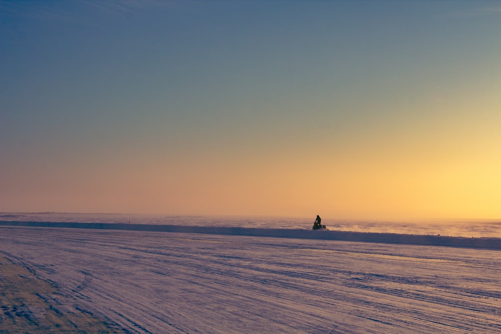 a person riding a snowboard down a snow covered road