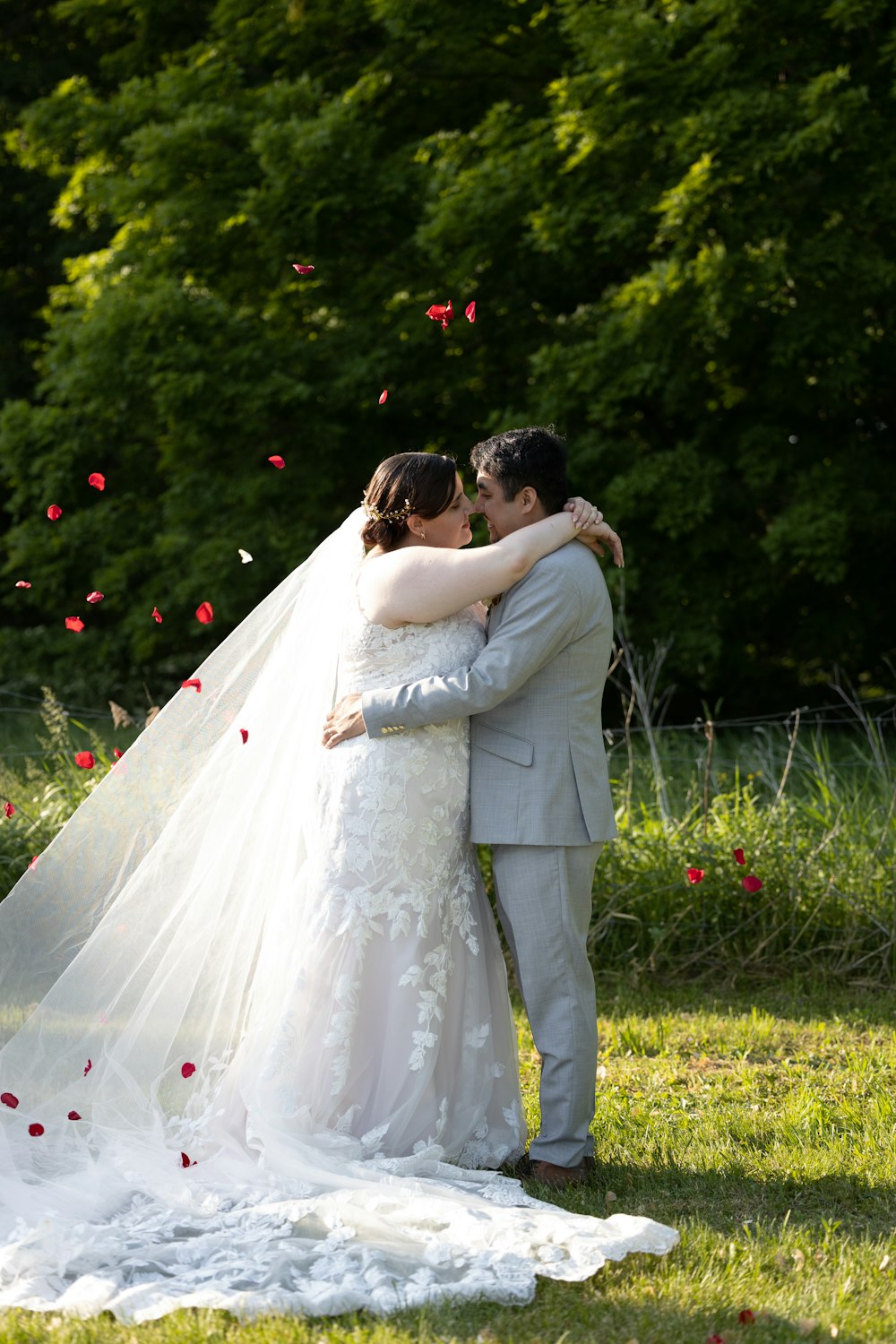a bride and groom embracing in a field