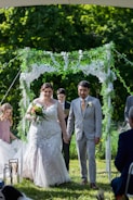 Bride walking down the aisle with her father in a charming garden setting.