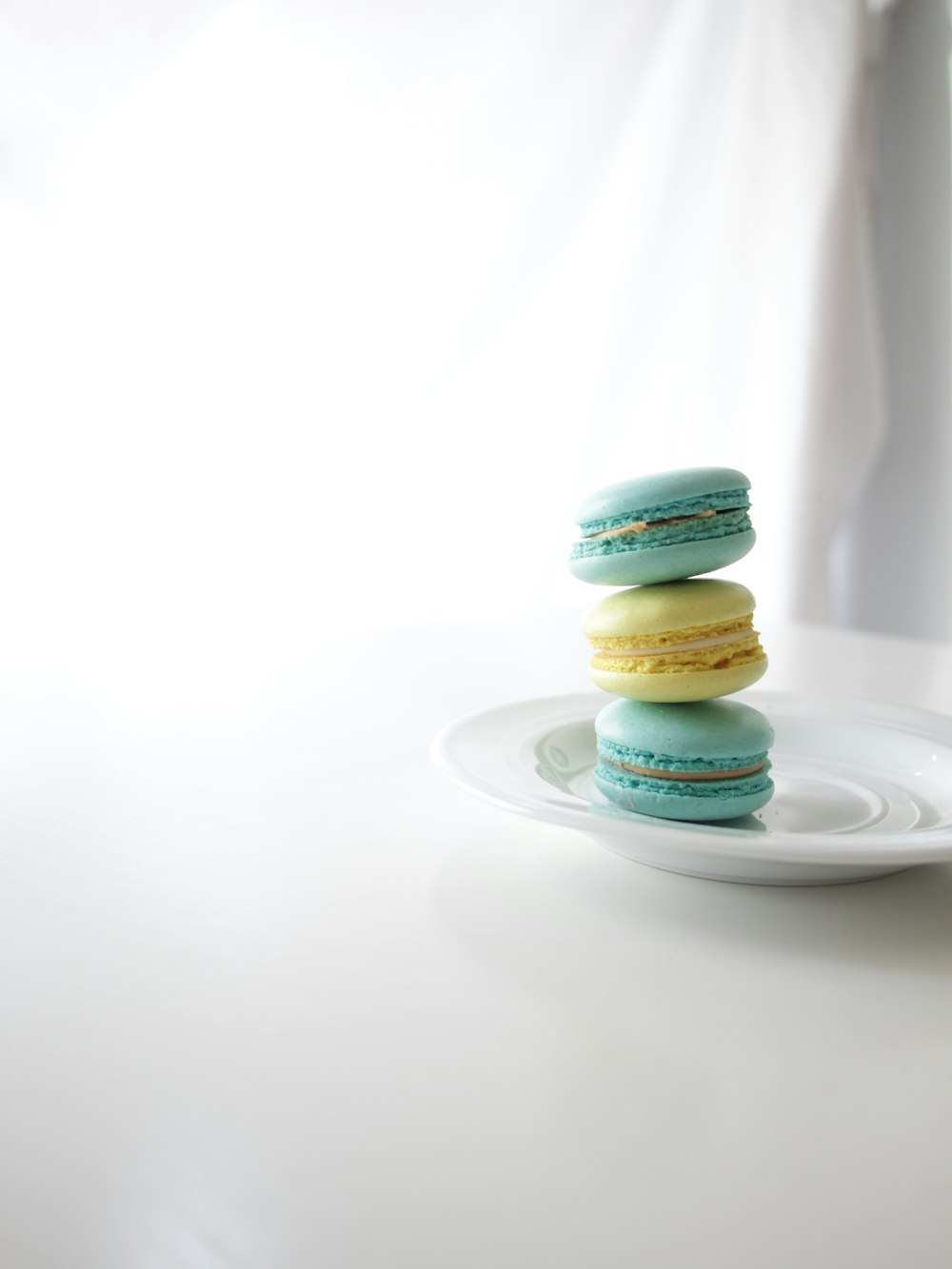 a white plate topped with three blue and yellow macaroons