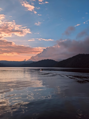 A serene boat cruising on Lake Annecy with mountains in the background during sunset.