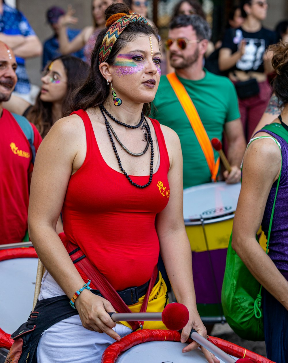 a woman in a red tank top is holding a drum