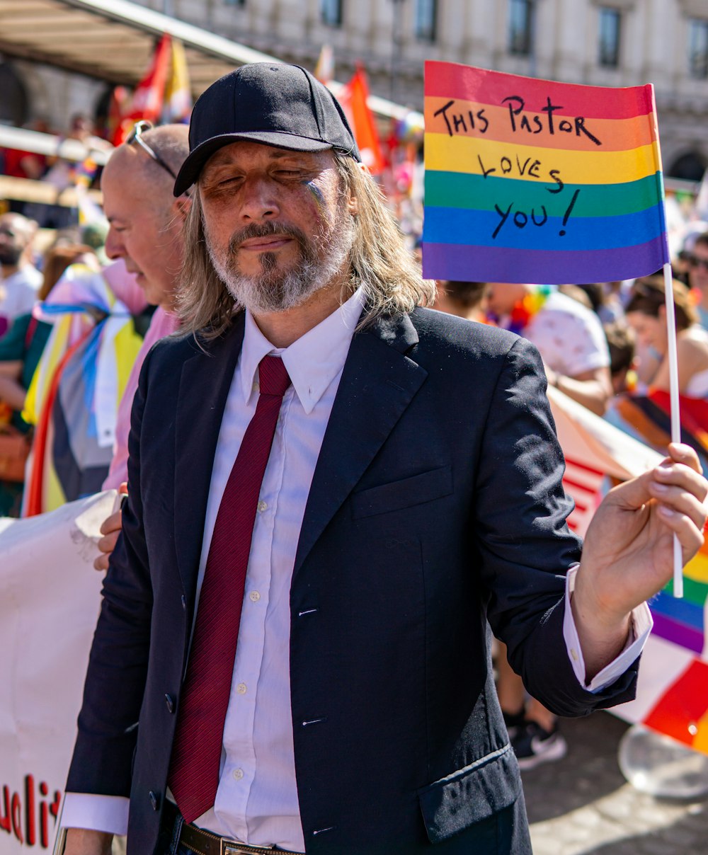 a man in a suit and tie holding a rainbow flag