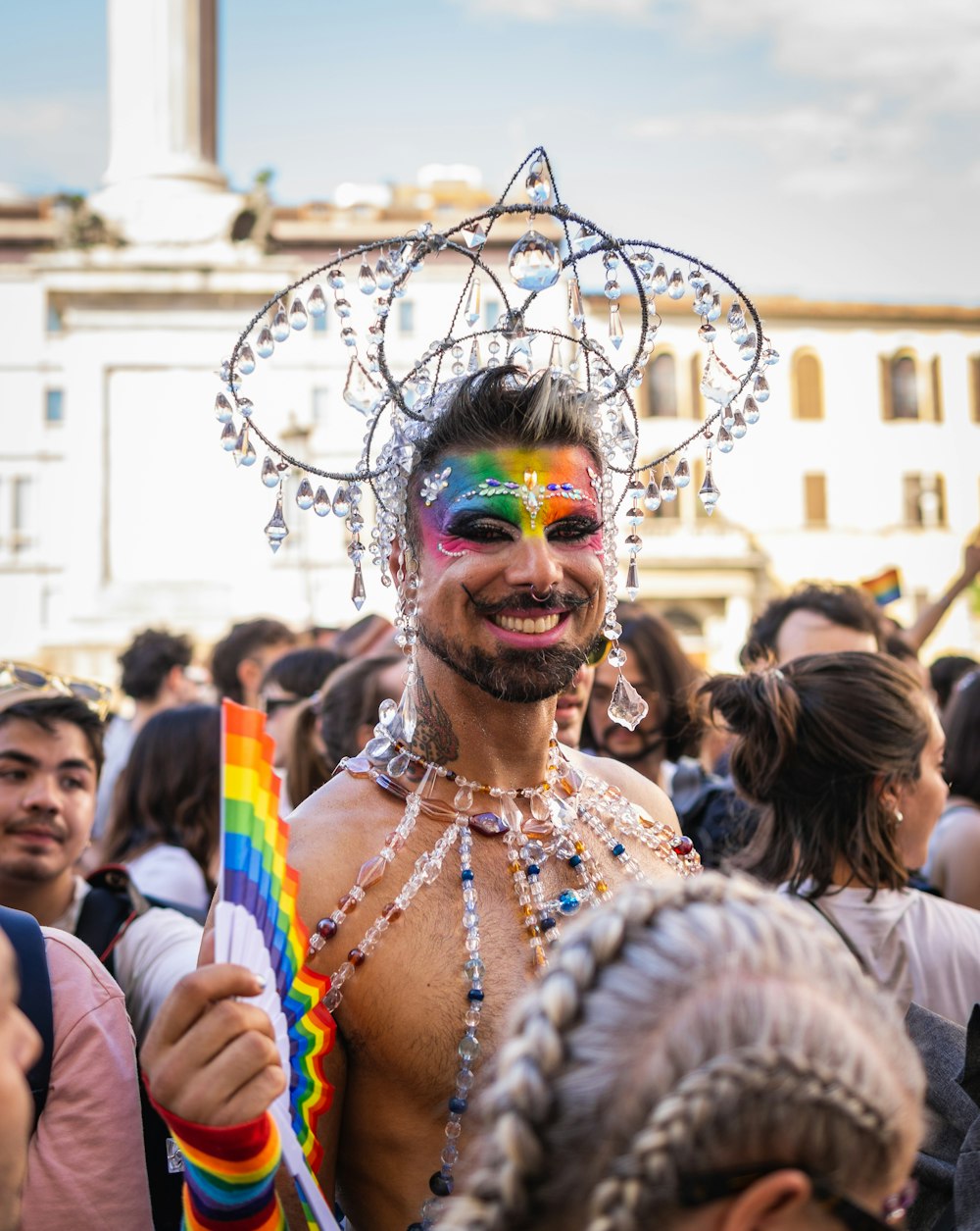 a man with a rainbow face paint holding a flag