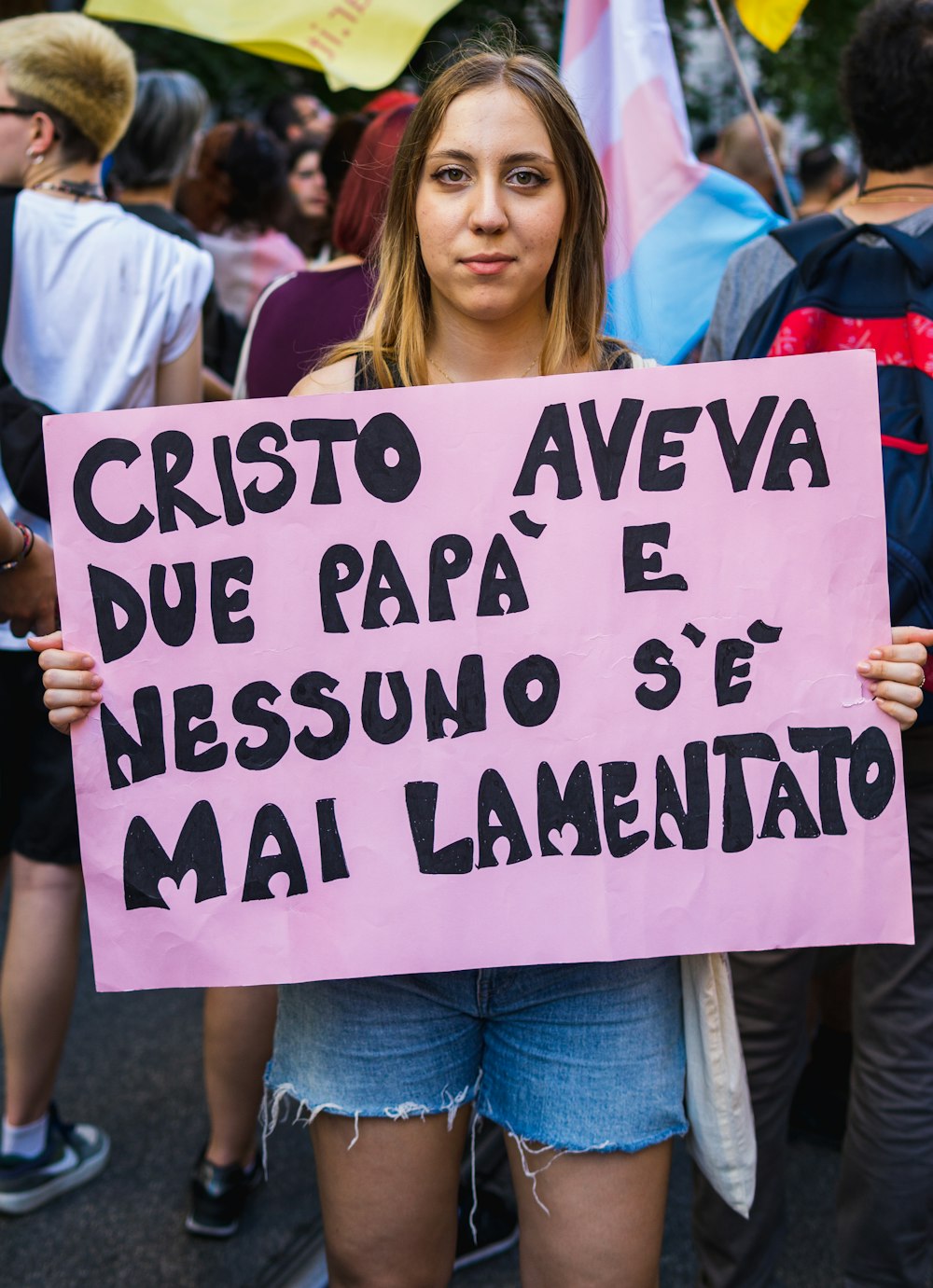 a woman holding a sign that says cristoo aveva due papa e ness