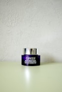A Clinique smart clinical repair wrinkle correcting eye cream jar is placed on a light-colored surface. The jar is purple with a metallic silver lid, and the label text is in white.