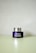 A Clinique smart clinical repair wrinkle correcting eye cream jar is placed on a light-colored surface. The jar is purple with a metallic silver lid, and the label text is in white.
