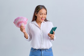 A confident person holding cash and a loan approval document.