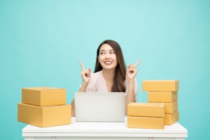 a woman sitting at a table with a laptop surrounded by boxes