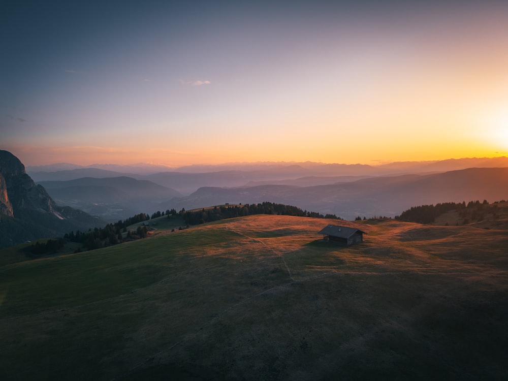 the sun is setting over a grassy hill