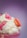 A dessert featuring whipped cream, small pink chocolate pieces labeled 'milk', and a pink macaron on top of the dessert. The background is a soft gradient of purple.